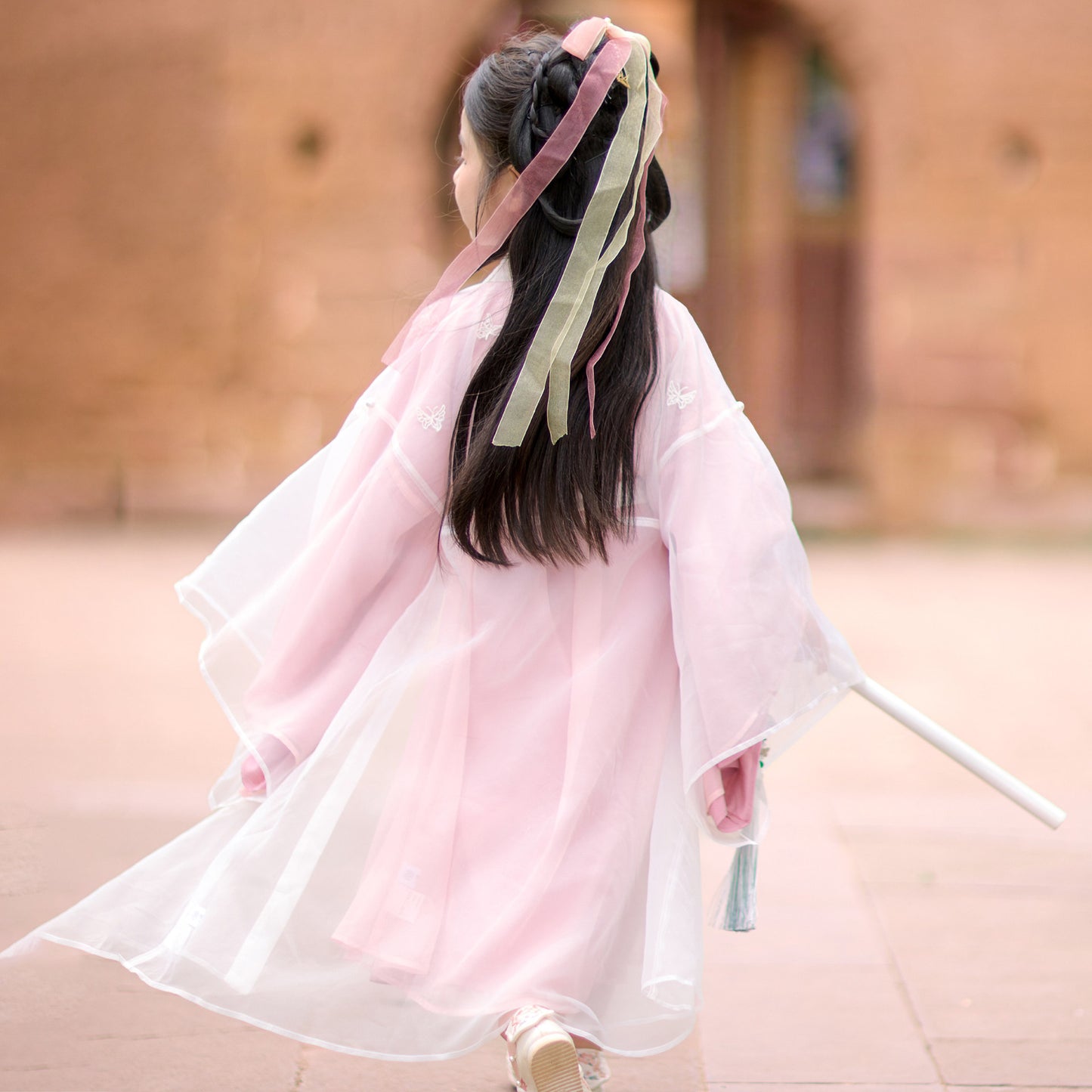 Person wearing a traditional pink garment with a blurred background