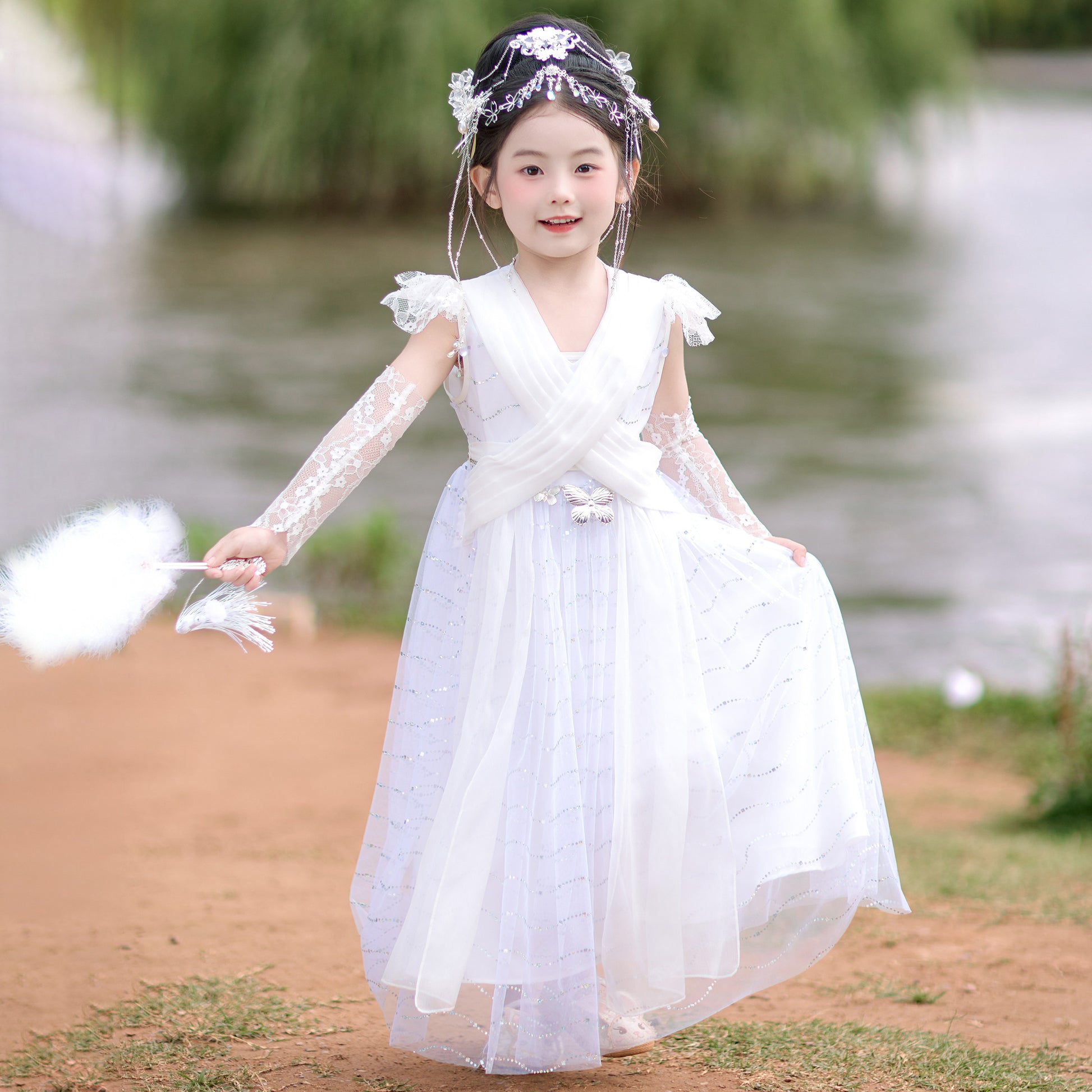 Young girl in a white dress standing outdoors near a body of water.