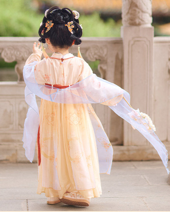 Child in traditional Chinese attire standing on a stone platform with greenery in the background