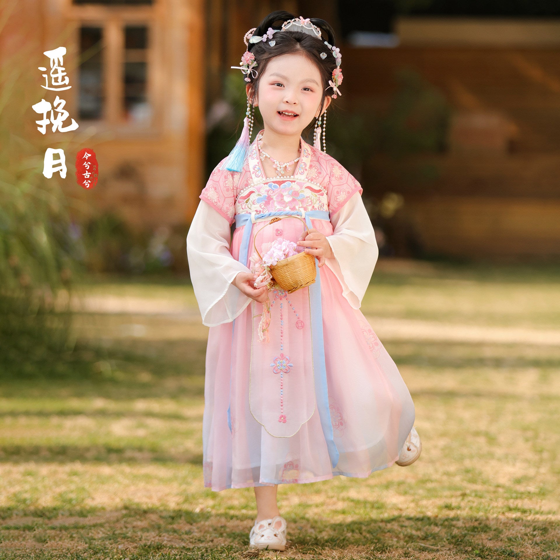 Child in traditional pink and white outfit holding a small round object outdoors.