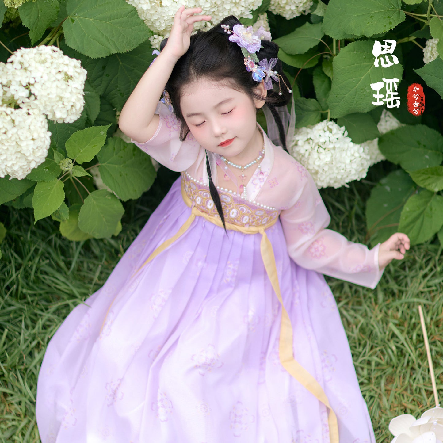 Young girl in a traditional outfit standing among white flowers and green leaves