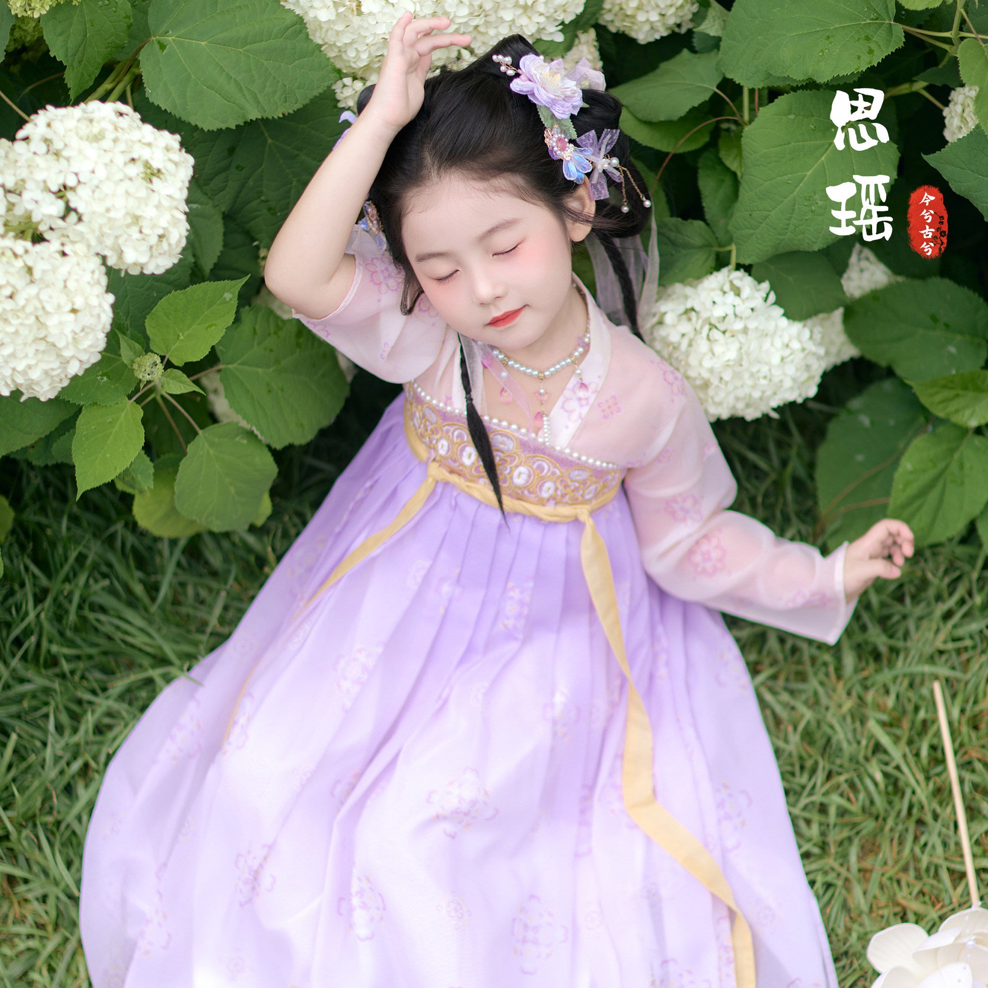 Young girl in a traditional outfit standing among white flowers and green leaves