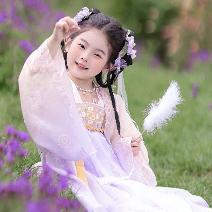 Child in traditional attire sitting among purple flowers