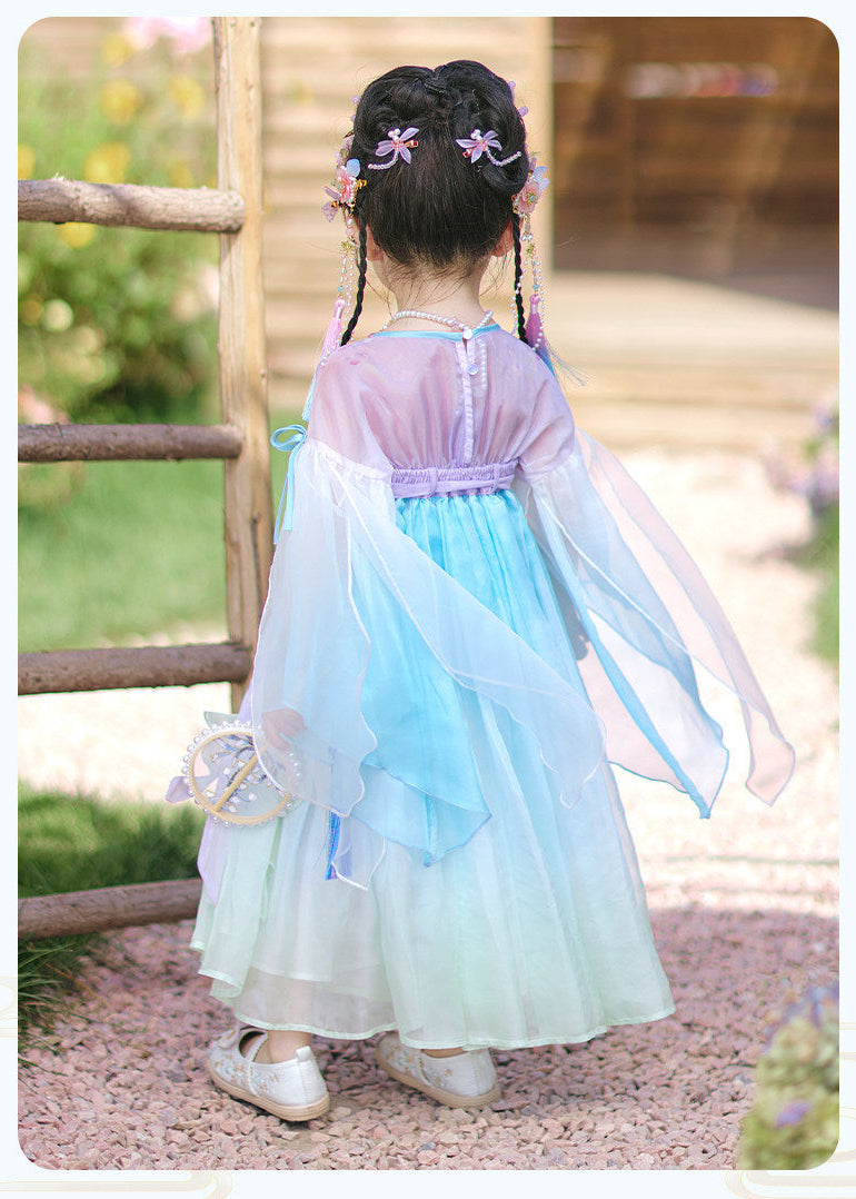 Child wearing a traditional outfit with a gradient dress in a garden setting