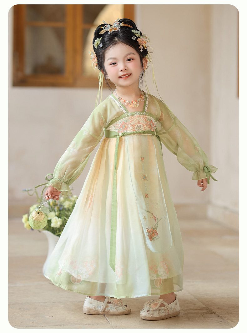 Child in a traditional outfit with floral headpiece and floral decorations indoors.