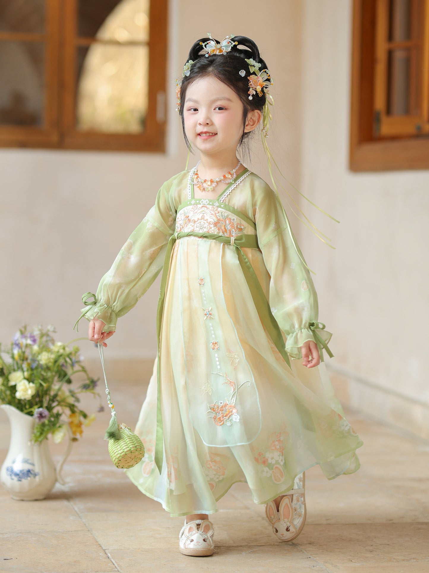 Young girl in a traditional light green dress with floral patterns indoors.
