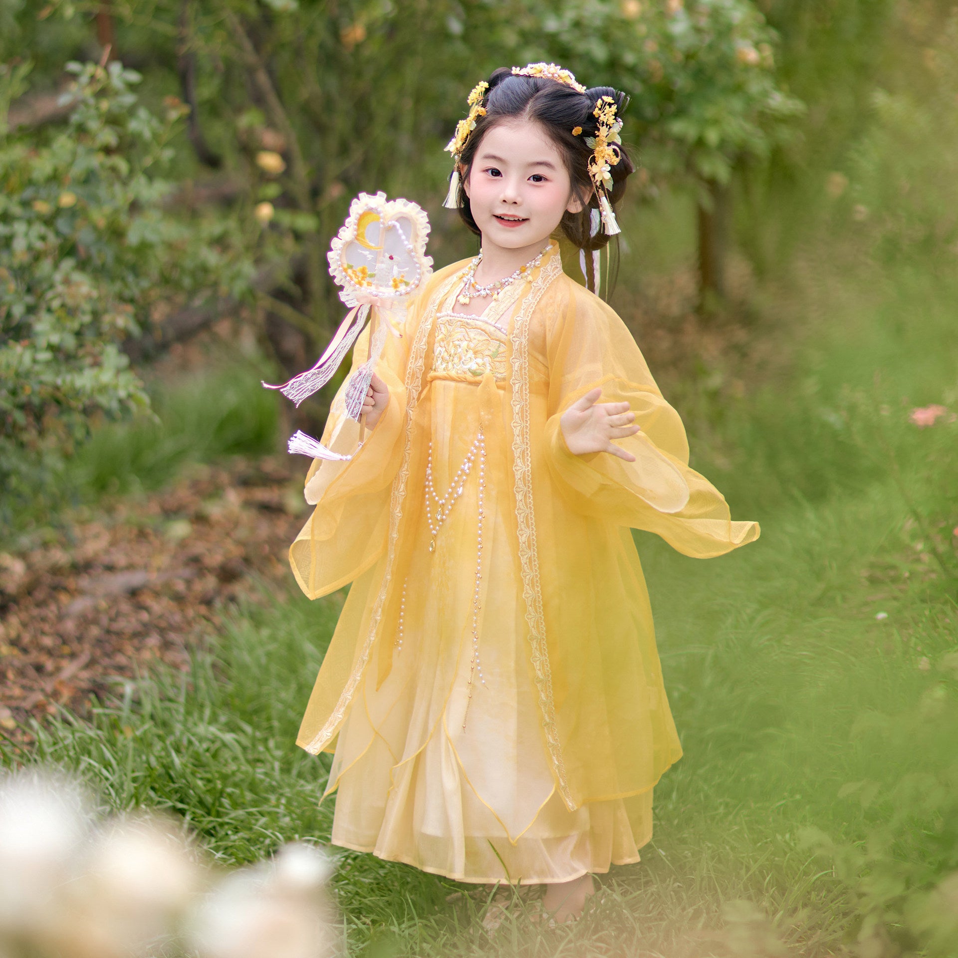 Young girl in a yellow traditional dress standing in a garden