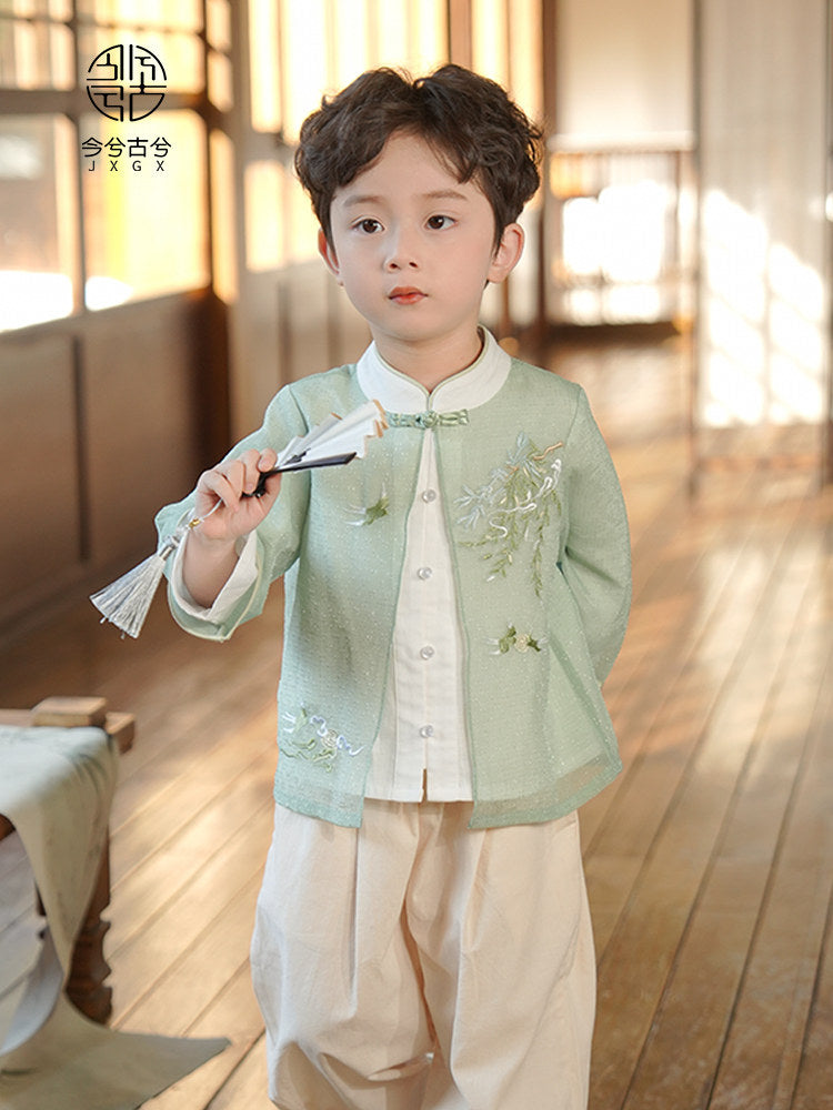 Child wearing a traditional outfit with floral embroidery in a warm-toned room.