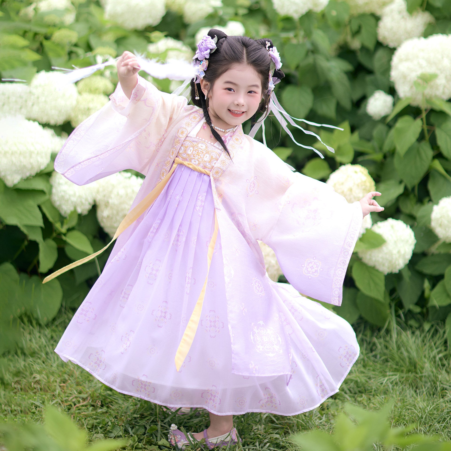 Child in a traditional outfit standing in front of white flowers