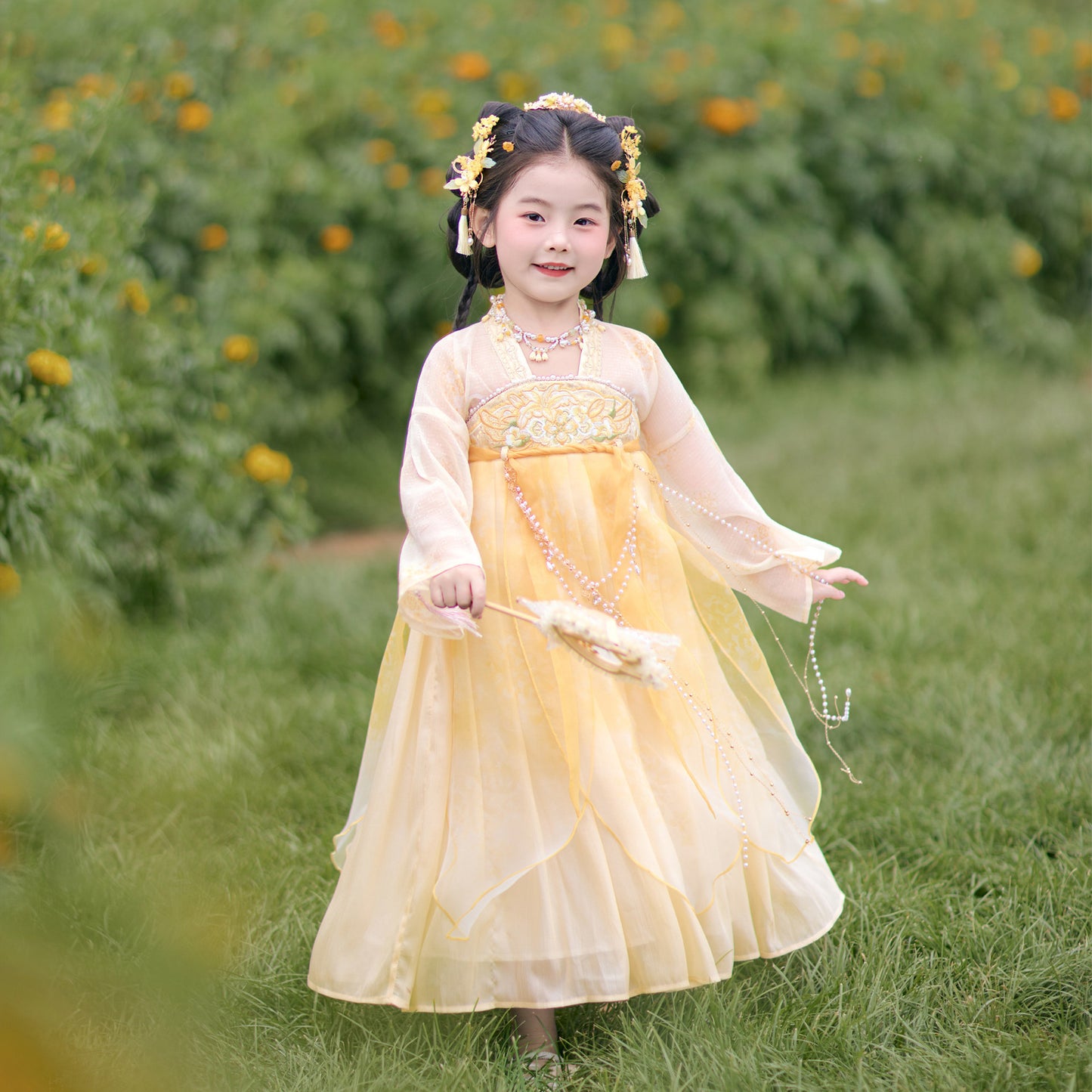 Young girl in a yellow dress standing in a field of flowers