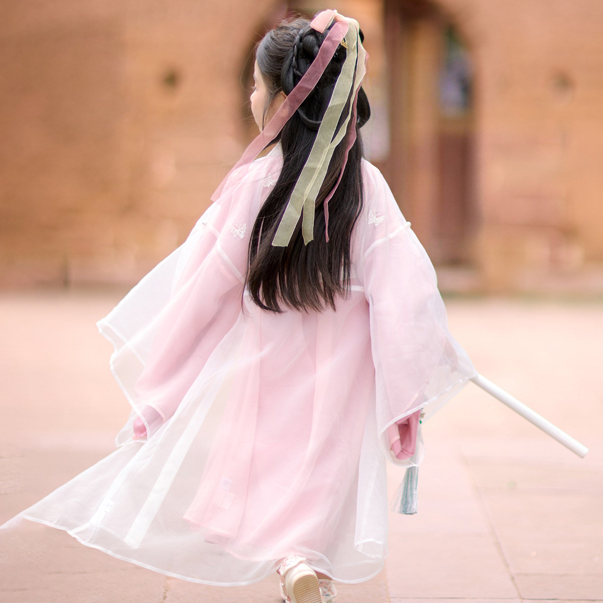 Person wearing a traditional pink garment with a blurred background