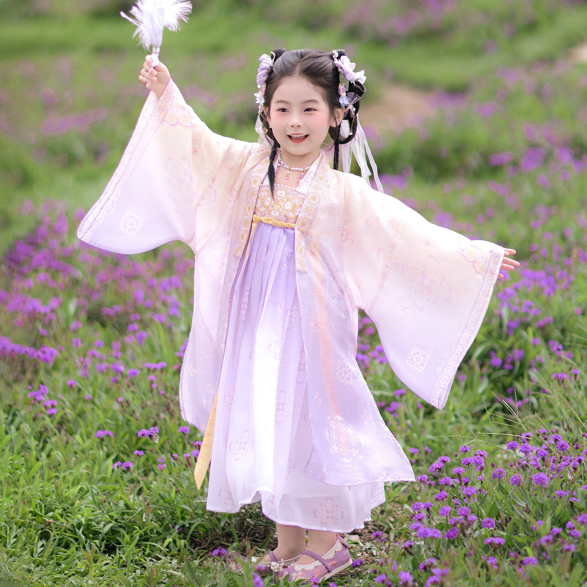 Child in traditional attire standing in a field of purple flowers