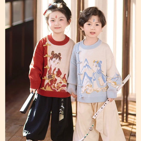 Two children in traditional outfits standing indoors with wooden flooring and a neutral background.